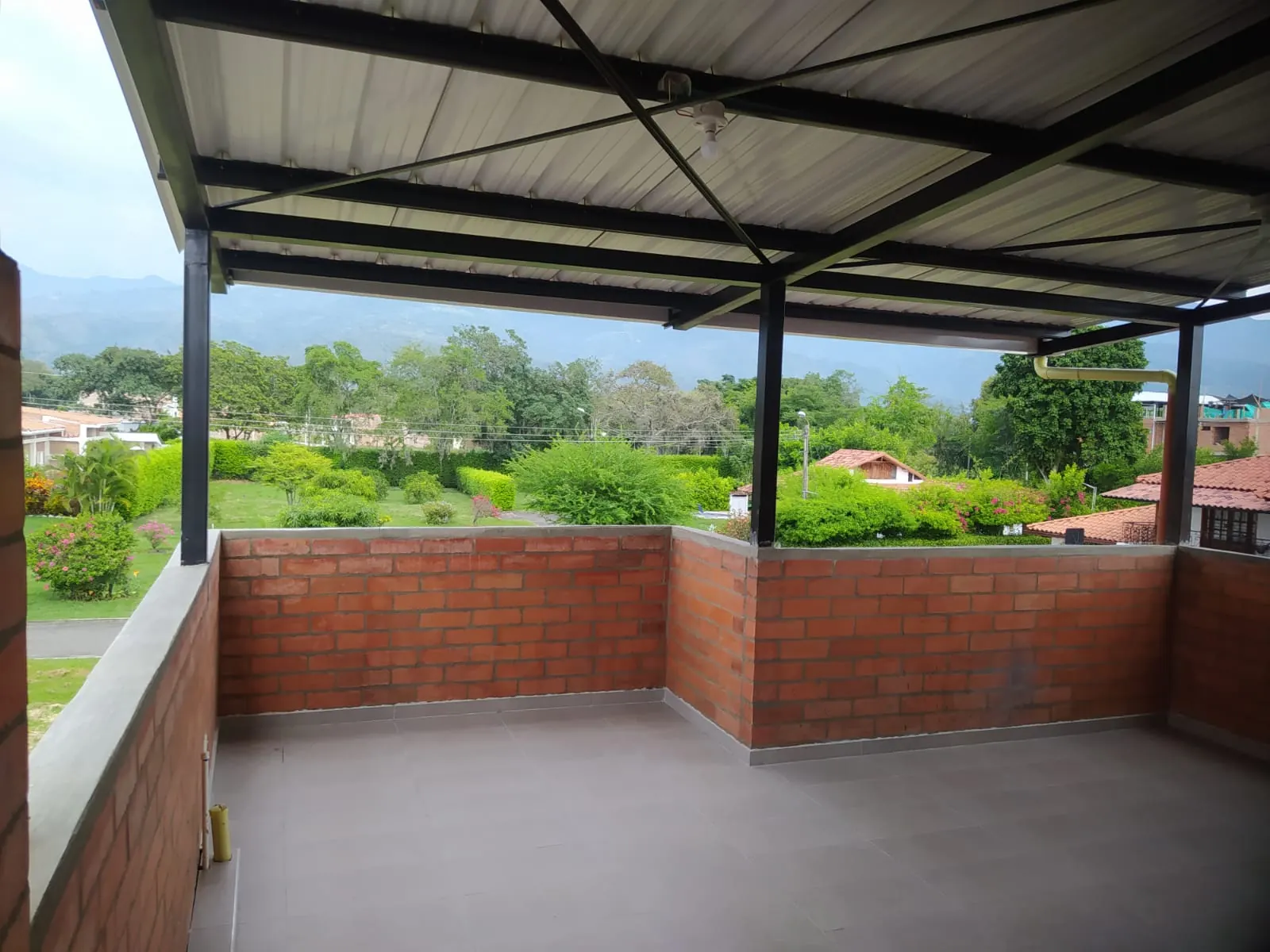 Terraza cubierta con vista a jardines y montañas